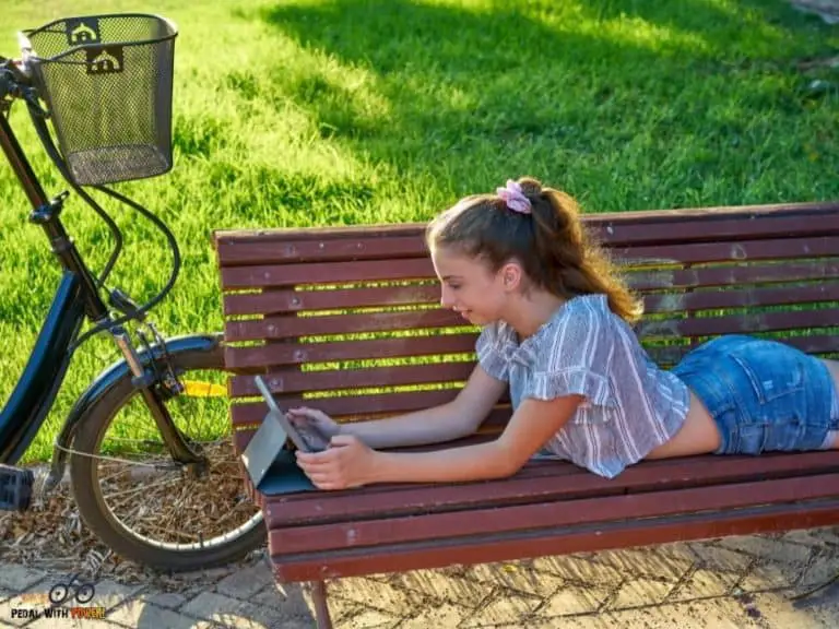 girl on a bench by her bike with laptop